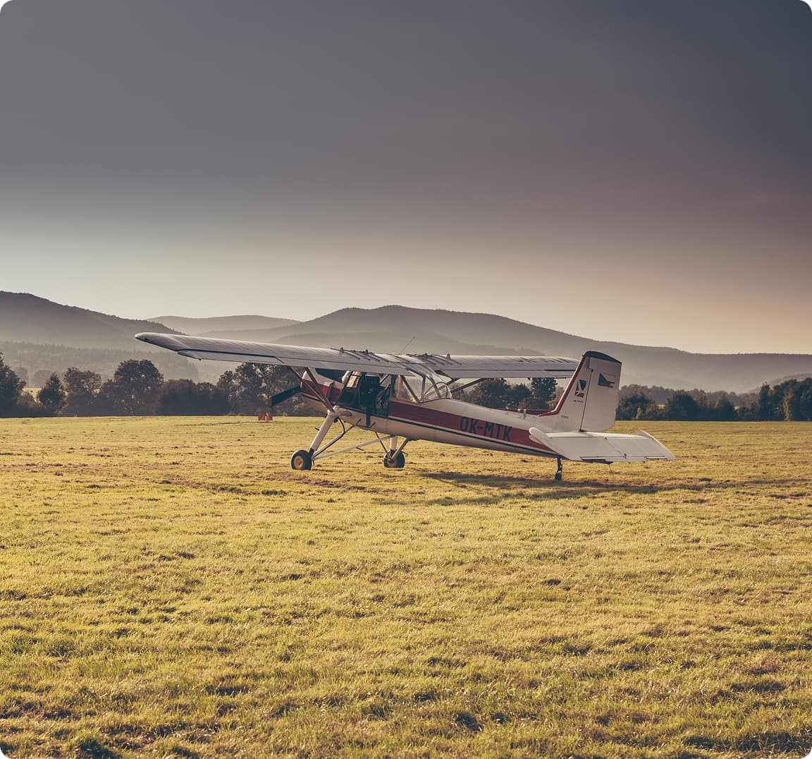 A small plane parked on the grass runway at Sunset Hill Farm